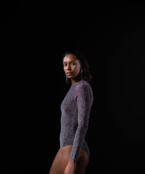 Woman in a calm yoga pose on a dark background.